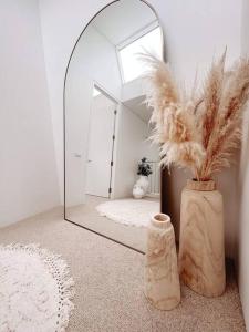 a room with a mirror and a vase with feathers at The Cove Beach Front Luxury House in Port Fairy