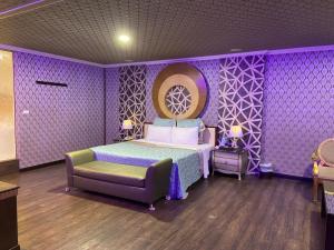 Dormitorio púrpura con cama y silla en Huang Xing Motel en Pingtung City