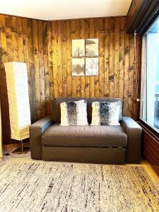 - un canapé dans une chambre dotée d'un mur en bois dans l'établissement Cosy Studio for 5 near ski lift, Les Gentianes, à Les Collons