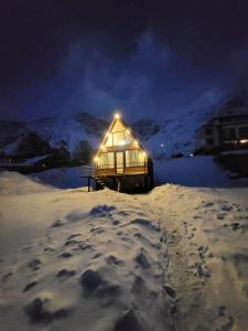 uma pequena cabana na neve à noite em Rocky Views em Kazbegi