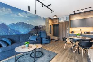 a living room with a blue couch and a mountain mural at Stone Hill Apartament Wellness z basenem jakuzi saunami prywatnym garażem i rowerami w cenie in Szklarska Poręba