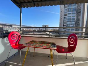 zwei rote Stühle und eine Bank auf dem Balkon in der Unterkunft Amazing penthouse in Sarajevo