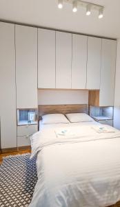 a bedroom with a large bed with white cabinets at Apartman Una in Kragujevac