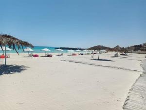 a beach with umbrellas and chairs and the ocean at El Obayed Apartments Armed Forces in Marsa Matruh