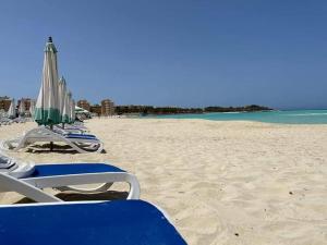 a group of chairs and umbrellas on a beach at El Obayed Apartments Armed Forces in Marsa Matruh