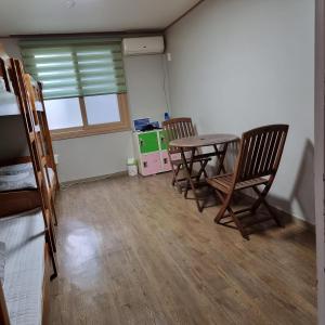Habitación con 2 sillas, mesa y ventana en You&I Guesthouse, en Jeju