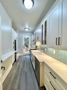 a large kitchen with white cabinets and wooden floors at Vacation Retreat with Pool, Gym, Kitchen in Sugar Hill