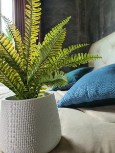 a plant in a white vase sitting on a bed at Bansuanrimnam Pakchong Resort in Pak Chong