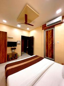 a bedroom with a large bed with a ceiling fan at AVIRAHI HOTEL in Mumbai