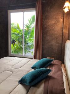 a bedroom with a large window and a bed with pillows at Bansuanrimnam Pakchong Resort in Pak Chong