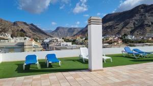 a group of chairs on a roof with mountains in the background at BEACH SIDE in Puerto de Mogán
