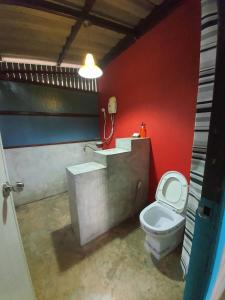 a bathroom with a toilet and a red wall at Bansuanrimnam Pakchong Resort in Pak Chong