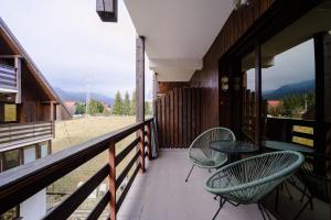 ein Balkon mit zwei Stühlen und einem Tisch in der Unterkunft Forest Nest with mountain view in Buşteni