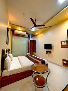 Schlafzimmer mit einem Bett, einem Tisch und einem TV in der Unterkunft AVIRAHI HOTEL in Mumbai