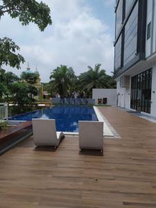 2 sillas sentadas en una terraza junto a una piscina en DeAr UC Apartment en Surabaya