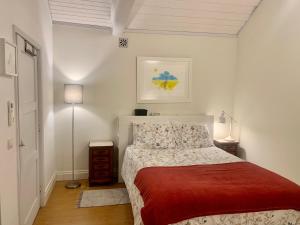 um quarto branco com uma cama com um cobertor vermelho em Casa do Paço Aveiro HolidayHome em Aveiro