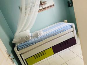 a small bed in a room with a curtain at Maelya House in Sainte-Anne