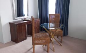 uma sala de jantar com uma mesa de vidro e 2 cadeiras em Revive Haven Guesthouse em Roodepoort