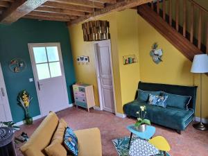 a living room with a green couch and yellow walls at Les suites d'Élise - Suite Louane in Grumesnil