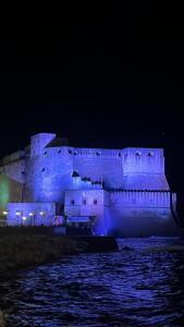 een groot kasteel wordt 's nachts blauw verlicht bij casa vacanze a casa di ciro in Napels