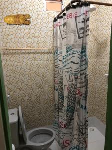 a bathroom with a toilet and a shower curtain at Chalé Panulirus in Icapuí