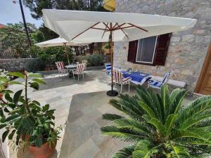 a patio with a table and an umbrella at Christiana’s Stone Villa in Hydra