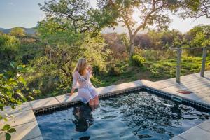 een vrouw staat in een zwembad bij Kruger Cliffs Lodge - Absolute privacy guaranteed in Hoedspruit