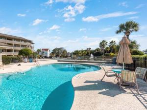 una piscina con sombrilla, mesa y sillas en Lighthouse Point 20A, en Tybee Island