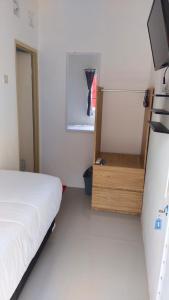 um pequeno quarto com uma cama e um frigorífico em D'Ariska Rooms Homestay em Jombang
