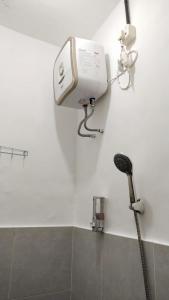 a bathroom with a shower and a hair dryer on the wall at D'Ariska Rooms Homestay in Jombang