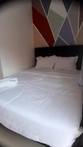 uma cama com lençóis brancos e almofadas num quarto em D'Ariska Rooms Homestay em Jombang