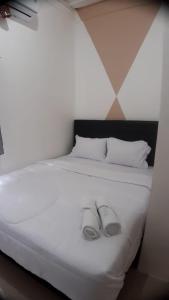 a white bed with two wedding shoes on it at D'Ariska Rooms Homestay in Jombang