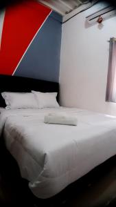 a white bed with a red white and blue wall at D'Ariska Rooms Homestay in Jombang