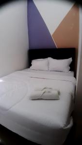 a bedroom with a white bed with a purple accent at D'Ariska Rooms Homestay in Jombang