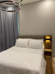 sypialnia z dużym białym łóżkiem z żyrandolem w obiekcie Datum Jelatek Sky Residence KLCC SkyRing Linked to LRT and Mall w Kuala Lumpur