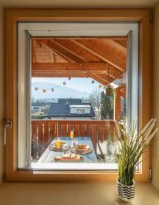 una finestra in una casa con tavolo con bicchieri da cibo e vino di Swiss Alps View Apartment - contactless self check-in a Thun