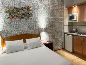 a bedroom with a white bed and a kitchen at Beatriz Charming Hostal in Torremolinos +99 photos