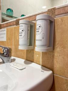 two buckets on the wall above a bathroom sink at Beatriz Charming Hostal in Torremolinos