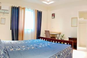 Un dormitorio con una cama azul y una ventana en DJL House Homestay -Bantayan Island, en Patao
