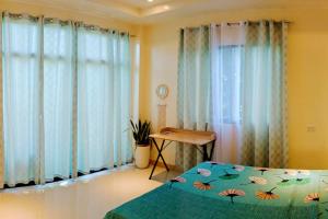 1 dormitorio con cama, mesa y ventanas en DJL House Homestay -Bantayan Island, en Patao