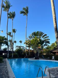 a swimming pool with palm trees in the background at Apartamentos Palo Coco in Las Terrenas
