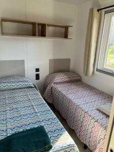 2 camas en una habitación pequeña con ventana en Agricampeggio Cà di Mazza, en Monzuno