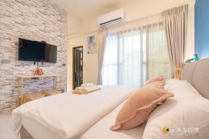 1 dormitorio con 1 cama blanca y TV en TING ZHU Homestay en Hualien