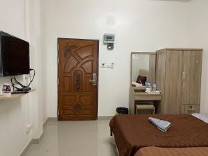 een kamer met een houten deur, een bed en een bureau bij ควีนเพลส สระบุรี Queenplace Saraburi in Sara Buri