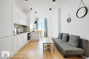 uma sala de estar com um sofá e uma cozinha em Piotrkowska Street I by LookAp em Łódź