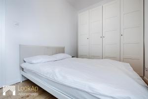 um quarto branco com uma cama grande e armários brancos em Piotrkowska Street I by LookAp em Lódź
