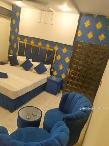 um quarto com uma cama e duas cadeiras azuis em Hotel Royal Luxury Multan em Multan