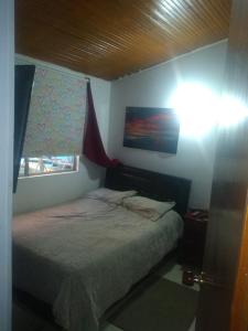 um pequeno quarto com uma cama e uma janela em cálida, acogedora habitación cerca a Unicentro de occidente em Bogotá