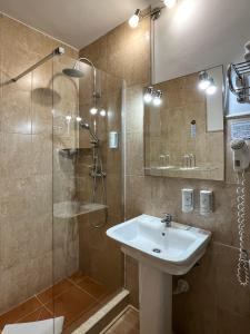 a bathroom with a sink and a glass shower at Beatriz Charming Hostal in Torremolinos