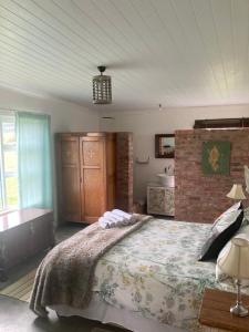 a bedroom with a large bed and a brick wall at Ou Werf Farm Cottage in Bredasdorp